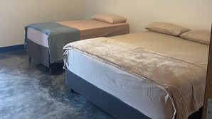 Una habitación con dos camas, una mesita y una lámpara en el techo.