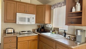 A kitchen with wooden cabinets, a white microwave, a toaster, and a coffee maker.
