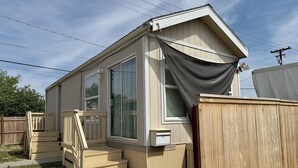 A single-story mobile home with a front porch, a sliding glass door, and a small attached garage.