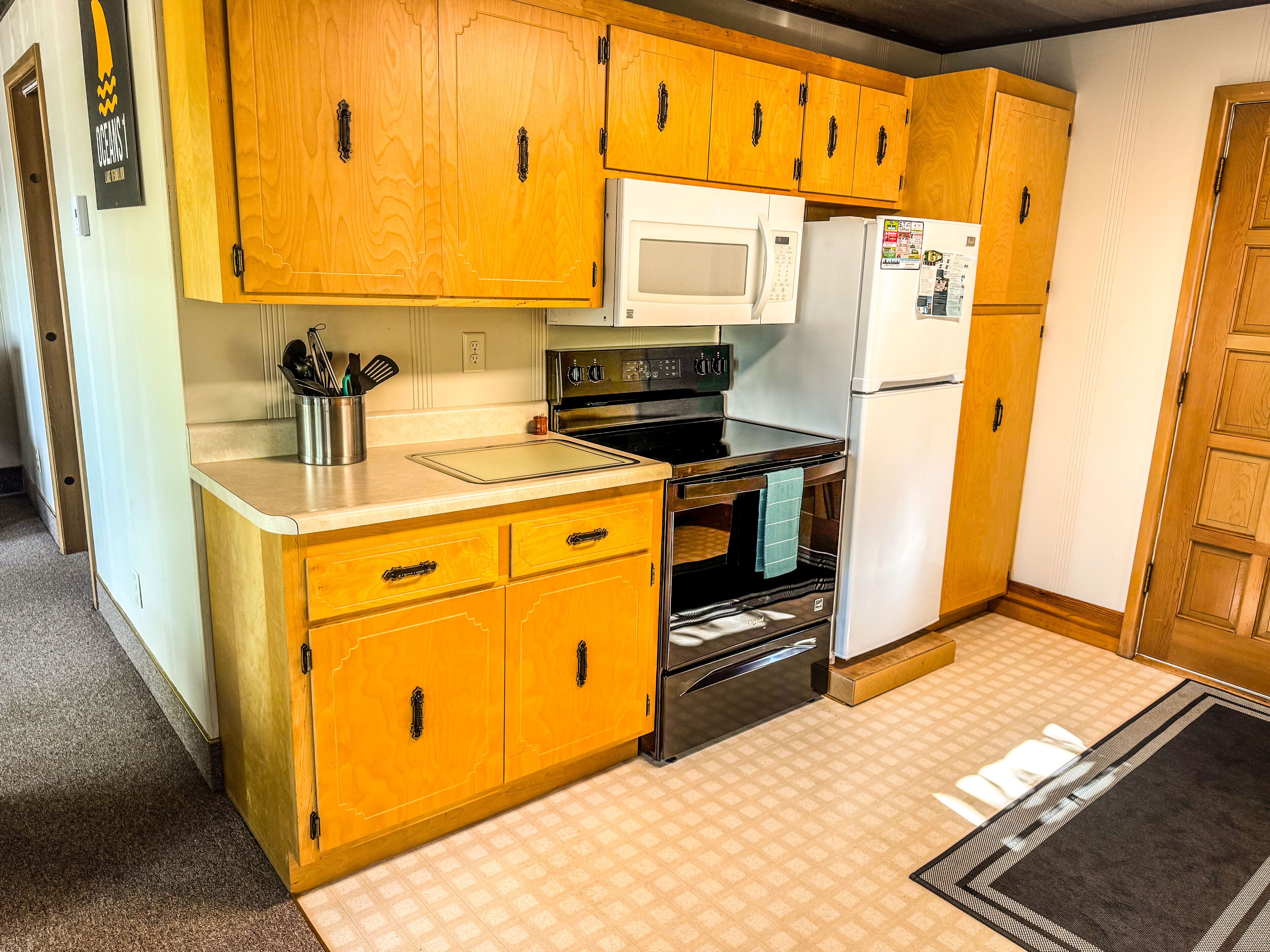 A kitchen with wooden cabinets, a microwave, a stove, and a refrigerator.