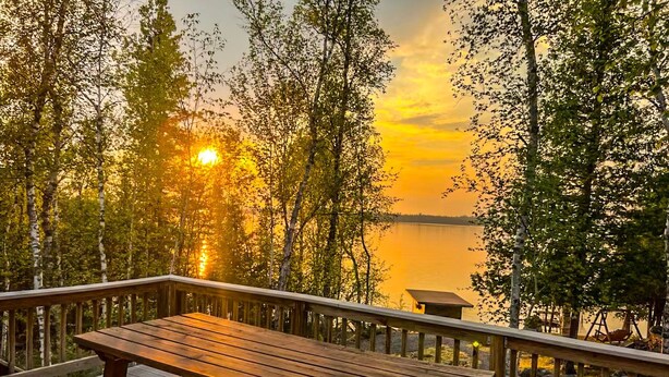 A wooden deck with a table and benches overlooking a lake at sunset. - Oceans 1 - A Frazer Bay Hideaway. Centrally Located! Boat Rentals also Available (Tower)
