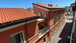 A red building with a tiled roof, balconies, and a clear sky. - CN014 - Cesenatico, new three-room apartment on the canal port (Cesenatico)