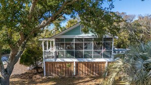 Une maison dotée d’un porche abrité, entourée d’arbres et d’une clôture en bois.