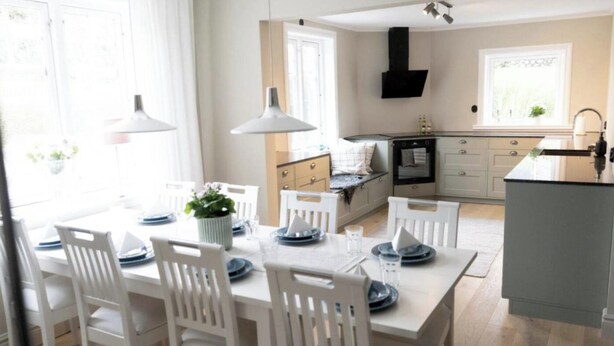 Una cocina moderna con armarios blancos, una isla central e iluminación colgante.