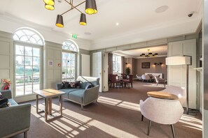 Una hall d'albergo con un'area salotto, una reception e un'area ristorazione.