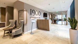 A reception area with a reception desk, a lounge chair, and a sign indicating the location of the fitness room, lounge, bedrooms, and a restaurant. - Edgbaston Park Hotel & Conference Centre (Birmingham)