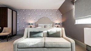 Ein modernes Schlafzimmer mit Schlafsofa, zwei Nachttischlampen, einem Wandpapier mit Muster und einem großen Fenster.