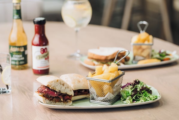 A dining table with a sandwich, a basket of fries, a salad, a bottle of ketchup, and a glass of wine. - Edgbaston Park Hotel & Conference Centre (Birmingham)