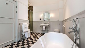 Ein Badezimmer mit Schachbrettboden, einer Badewanne, einem Waschbecken, einer Toilette und einer Dusche.