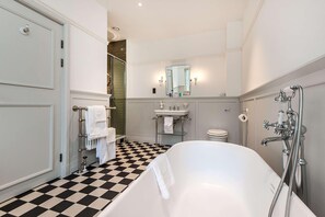 Un bagno con pavimento a scacchi, una vasca, un lavandino, un water e una doccia.