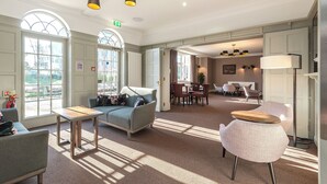 Una hall d'albergo con un'area salotto, una reception e un'area ristorazione.
