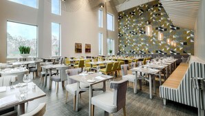A spacious dining area with multiple tables and chairs, large windows, and a geometric patterned wall. - Edgbaston Park Hotel & Conference Centre (Birmingham)