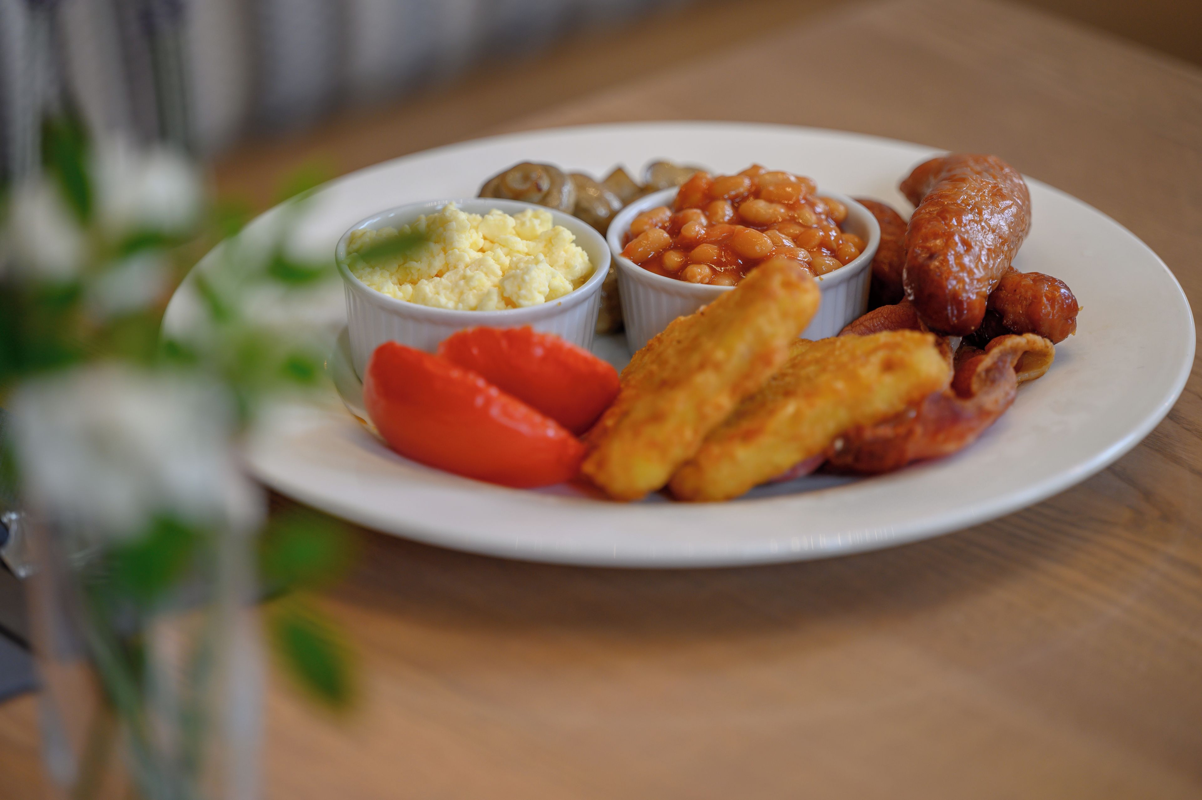Un plato de comida con salchichas, frijoles, huevos y tomates.