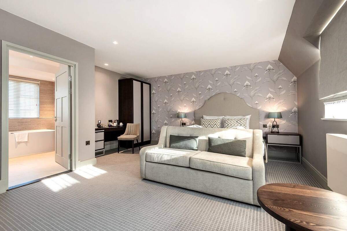 Un dormitorio moderno con sofá cama, escritorio y mesita de noche.