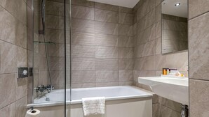 A modern bathroom with a glass-enclosed shower, a white bathtub, and a sink with toiletries. - Edgbaston Park Hotel & Conference Centre (Birmingham)