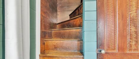 Un escalier en bois avec une rampe et une porte ornée d’un motif décoratif.