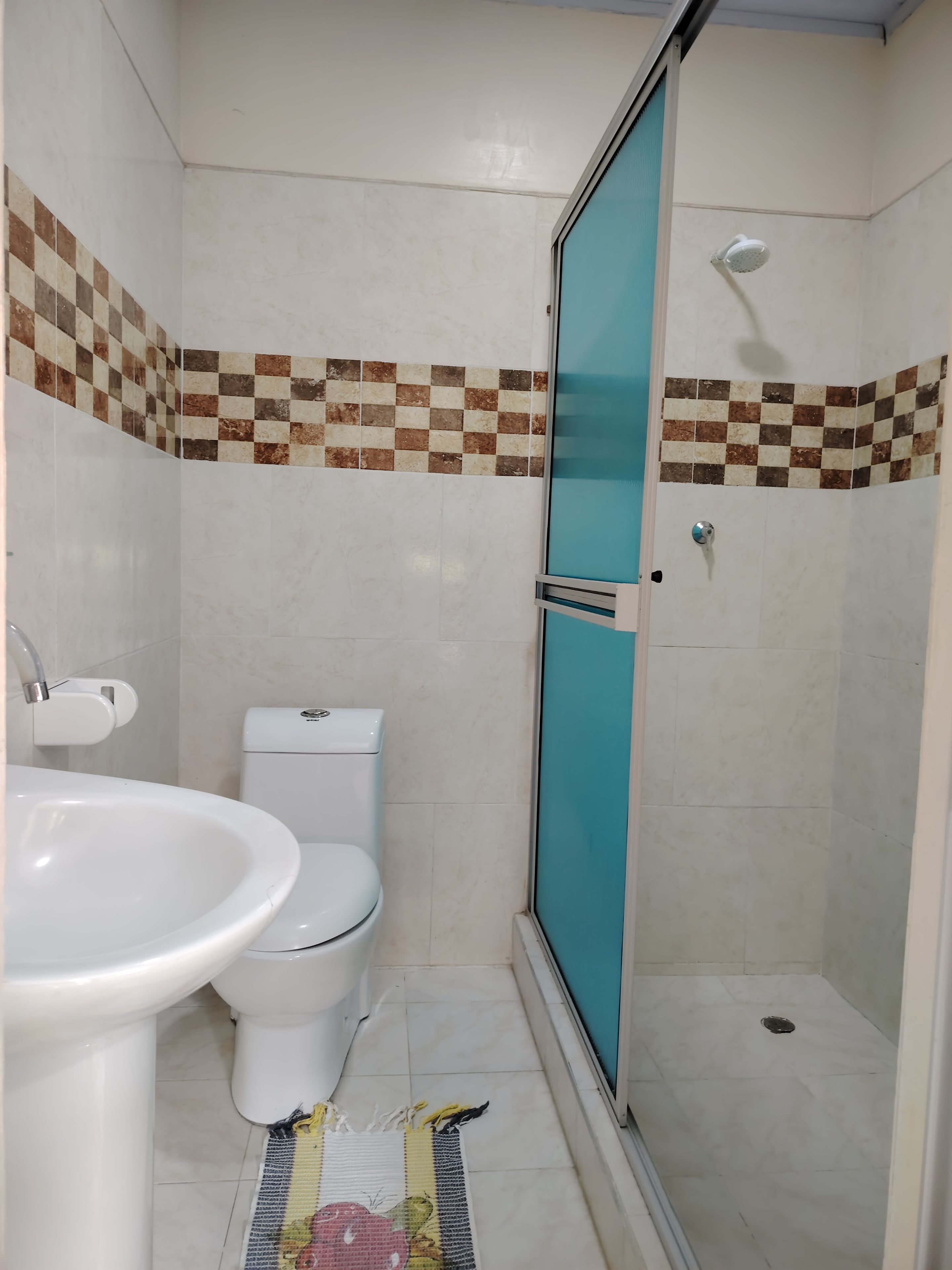 A bathroom with a toilet, sink, and shower area.