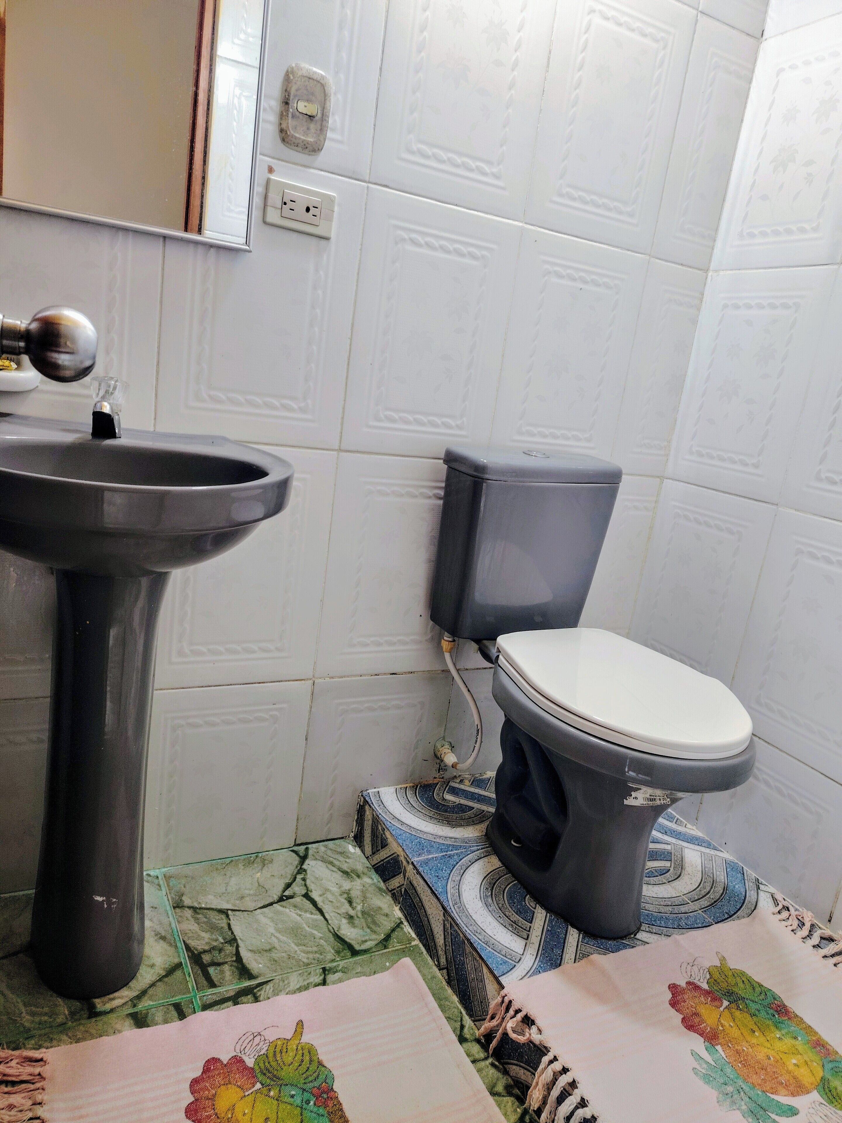 A bathroom with a pedestal sink, toilet, and patterned floor tiles.
