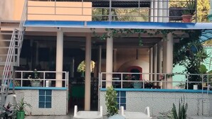 A building with a swimming pool, a covered area with seating, and potted plants. - Hotel Alto Amazonas  (Leticia)