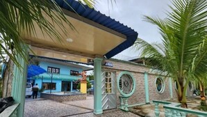 A building with a tiled floor, a covered entrance, and a statue. - Hotel Alto Amazonas  (Leticia)
