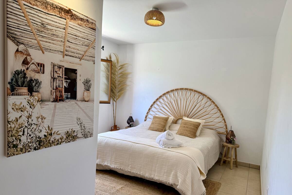 Une chambre à coucher avec un grand lit, une tête de lit ronde en bois, un tapis tissé et un luminaire fixé au plafond.