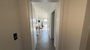 A hallway with a modern design, featuring a dark tiled floor and white walls.