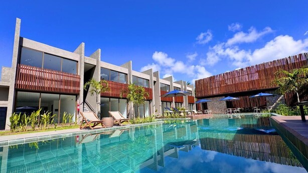 Un hôtel moderne doté d’une piscine, de chaises longues et de parasols.