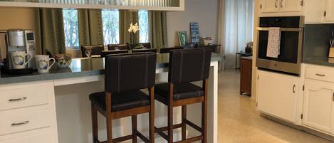A kitchen with a dining area, featuring a coffee maker, a microwave, and a refrigerator.