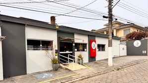 A hotel entrance with a modern design, a red sign, and a clear pathway leading to the entrance. - Hotel Veleiro (São Sebastião)