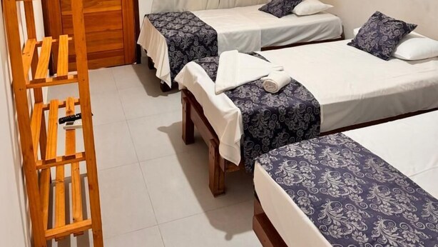 A room with two single beds, a wooden ladder, a ceiling fan, and a TV mounted on the wall. - Hotel Veleiro (São Sebastião)