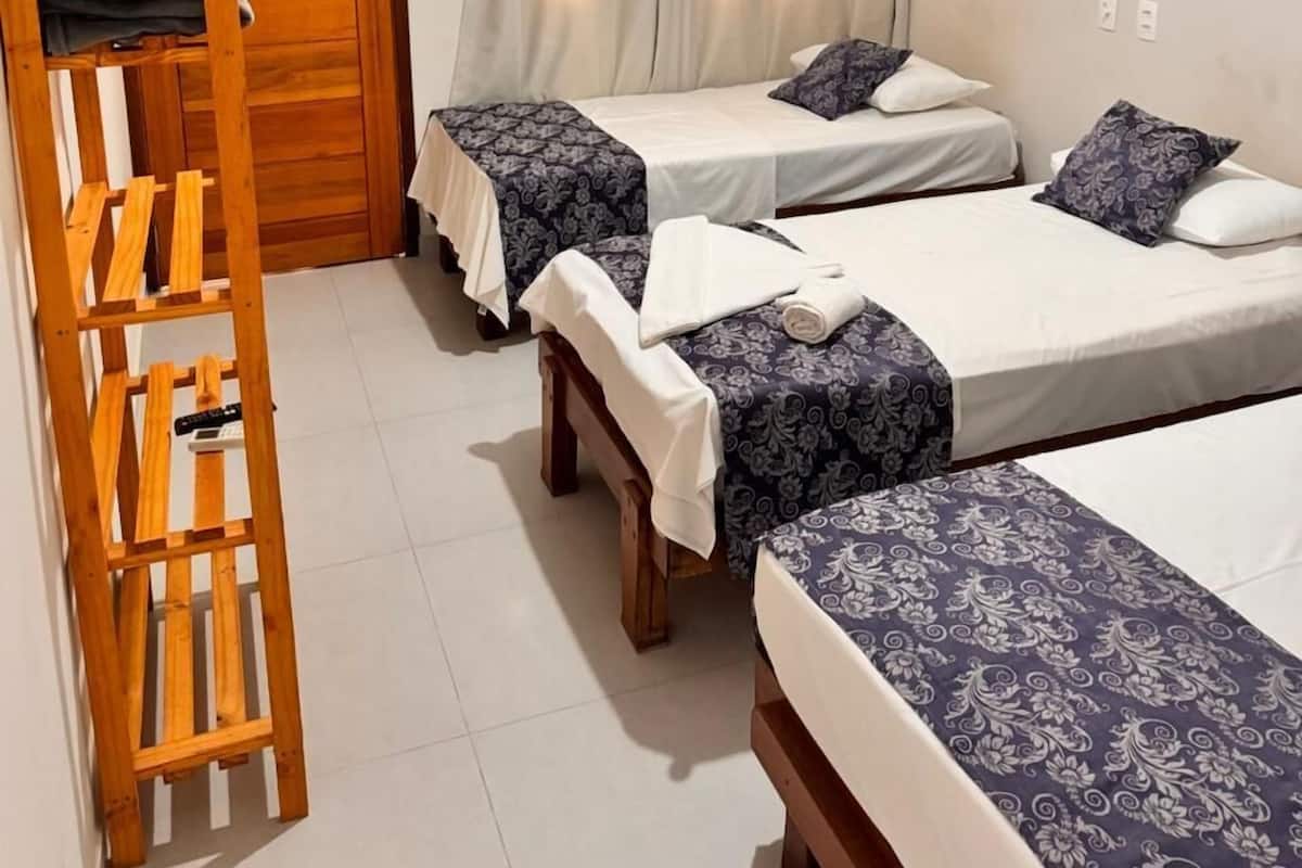 A room with two single beds, a wooden ladder, a ceiling fan, and a TV mounted on the wall.