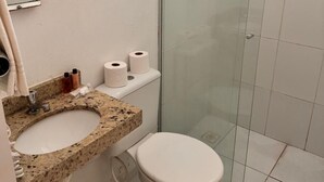 A bathroom with a granite countertop sink, a toilet, and a glass shower enclosure. - Hotel Veleiro (São Sebastião)