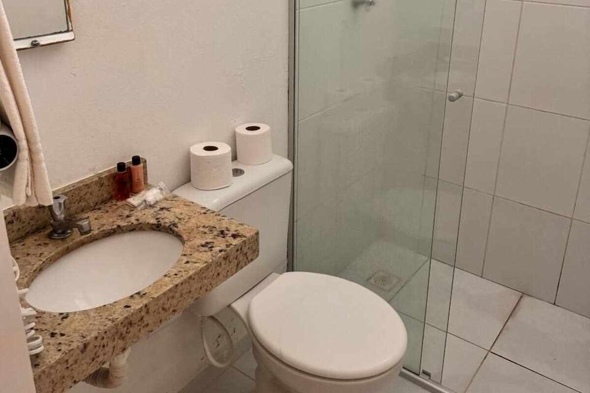 A bathroom with a granite countertop sink, a toilet, and a glass shower enclosure.