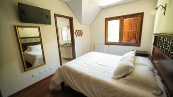 Une chambre à coucher avec un lit, un miroir, une télévision et une fenêtre avec des volets en bois.