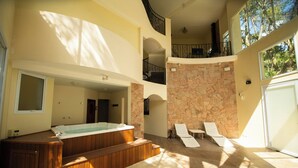 Een moderne spa-ruimte met een jacuzzi, lounge fauteuils en een stenen muur.