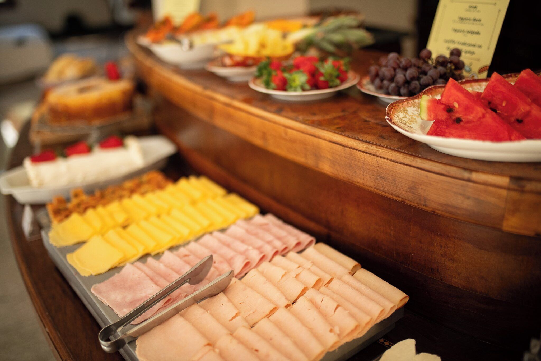 A buffet with various food items including meats, cheeses, fruits, and vegetables.
