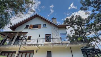 Une maison à deux étages dotée d’un balcon, d’une façade en pierre et d’une cheminée.