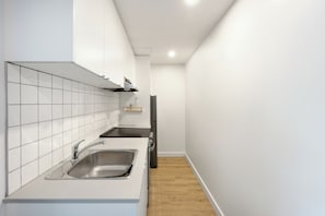 Uma cozinha moderna com azulejos brancos, eletrodomésticos de aço inoxidável e piso de madeira.