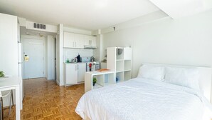 Een slaapkamer met een bed, een bureau en een kitchenette.