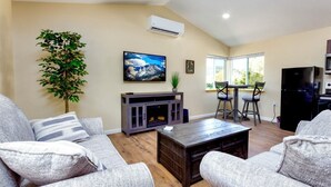 A living room with a sofa, coffee table, and a TV on the wall.