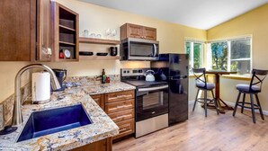 A modern kitchen with granite countertops, stainless steel appliances, wooden cabinets, and a built-in microwave.
