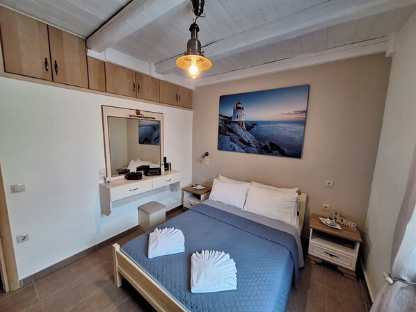 A bedroom with a bed, a nightstand, a dresser, a mirror, and a painting of a lighthouse.