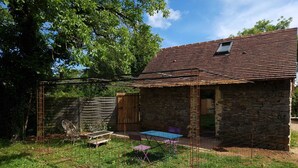 A rustic stone house with a metal roof, a wooden door, and a small window. - Gîte/Studio sleeps 2 with enclosed garden (pets welcome) and large shower. (Loubressac)