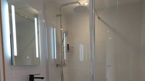 A modern bathroom with a glass-enclosed shower, a white sink, and a wooden vanity. - Gîte/Studio sleeps 2 with enclosed garden (pets welcome) and large shower. (Loubressac)