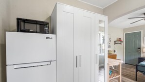 A compact kitchen with a white refrigerator, a microwave, and a wooden table. - Hummingbird Hideway Peaceful Lake View Cottage (Rockaway Beach)