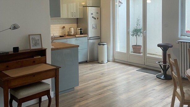 A modern kitchen with a central island, wooden dining table, and chairs.