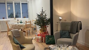 A living room with a Christmas tree, a dining area with a table and chairs, and a sofa.