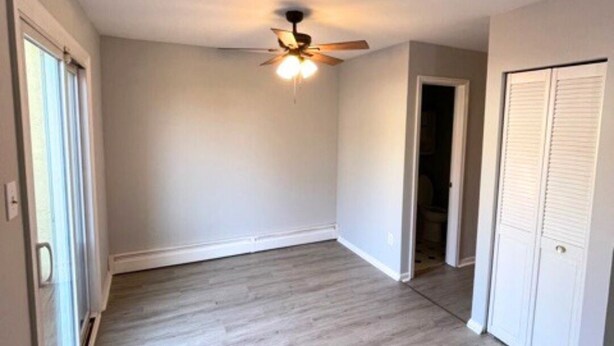 Une pièce dotée d’un ventilateur de plafond, d’une porte donnant accès à une salle de bain et d’un placard avec des portes coulissantes.