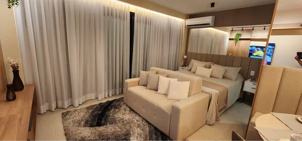 Een moderne hotelkamer met een bank, een bed, een televisie en een airconditioning.
