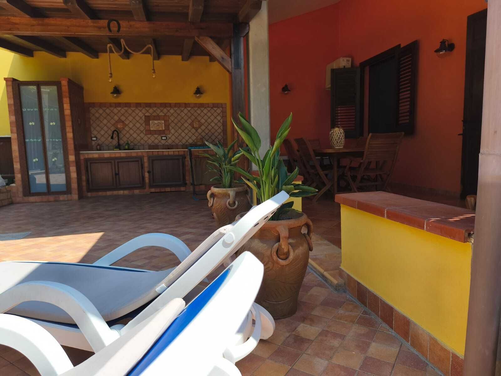 A patio with a pool table, lounge chairs, and a kitchen area with a tiled backsplash.